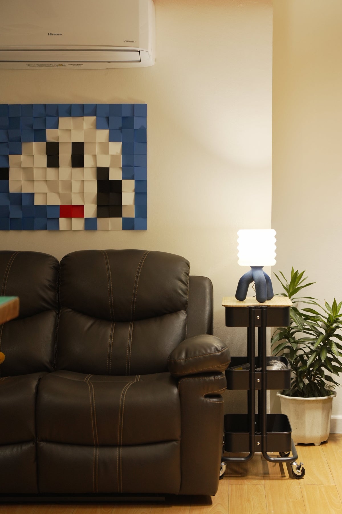 Tripp table lamp on a side table beside a sofa, under pixel wall art